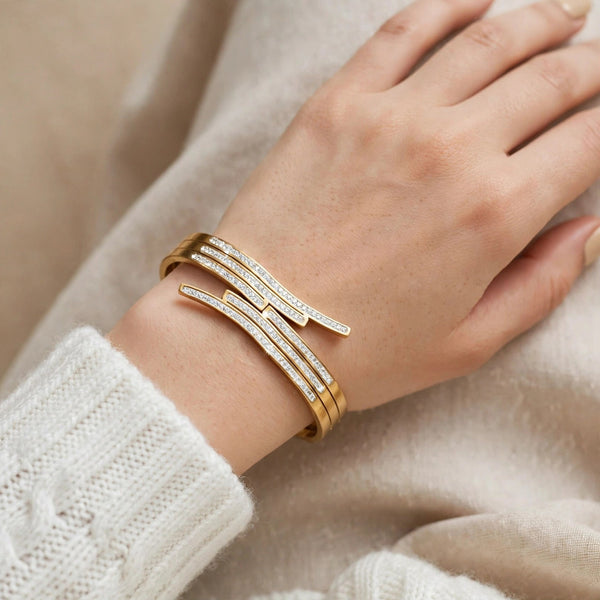 Hand wearing gold crossover cuff bangle with sparkling stones - Avenzra Gold Crossover Stone Bangle
