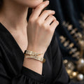 Model wearing gold crossover stone cuff bangle on dark background - Avenzra Gold Crossover Stone Bangle