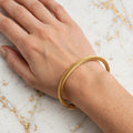 Wrist wearing golden twisted cable cuff bangle - Avenzra Golden Unisex Cuff Bangle